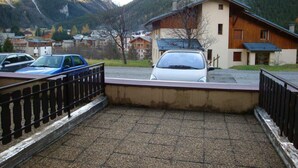 A parking area with a car in front of a building with a sloped roof, surrounded by mountains. - Ground floor, terrace, tv, ski locker, 22m², Pralognan-la-Vanoise (Pralognan-la-Vanoise)
