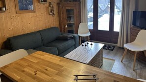 A cozy room with a wooden interior, a sofa, a dining table, and a view of a snowy mountain landscape through the glass door. - Ground floor, terrace, tv, ski locker, 22m², Pralognan-la-Vanoise (Pralognan-la-Vanoise)