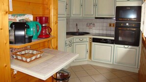 Una cucina compatta con mobili azzurri, un forno nero e una macchina da caffè.