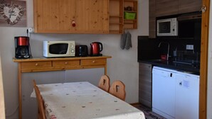 Une cuisine compacte dotée de meubles en bois, d’un four à micro-ondes, d’une machine à café et d’un lave-vaisselle.