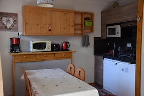 A compact kitchen with wooden cabinets, a microwave, a coffee maker, and a dishwasher.