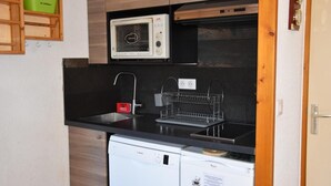 Une cuisine compacte équipée d’un four à micro-ondes, d’un évier et d’un petit réfrigérateur.
