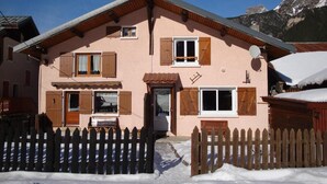 A two-story chalet with wooden shutters, a satellite dish, and a wooden fence in front. - Chalet, tv, 70m², Pralognan-la-Vanoise (Pralognan-la-Vanoise)