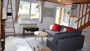 A cozy living room with a grey sofa, a small round table, a fur-covered bench, and a wooden ladder. - Chalet, tv, 70m², Pralognan-la-Vanoise (Pralognan-la-Vanoise)