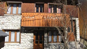Un bâtiment de style rustique, doté d’une façade en pierre, d’un balcon en bois et de nombreuses fenêtres.
