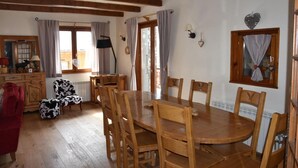 A cozy dining area with a wooden table and chairs, a red sofa, and a cow-patterned ottoman. - Chalet, terrace, balcony, tv, 200m², Pralognan-la-Vanoise (Pralognan-la-Vanoise)