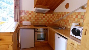A compact kitchen with a stove, oven, microwave, and sink.