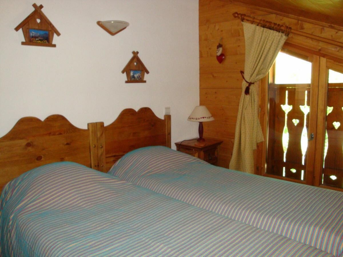 Une pièce en bois avec deux lits, une table de chevet, une lampe et une fenêtre avec des rideaux.