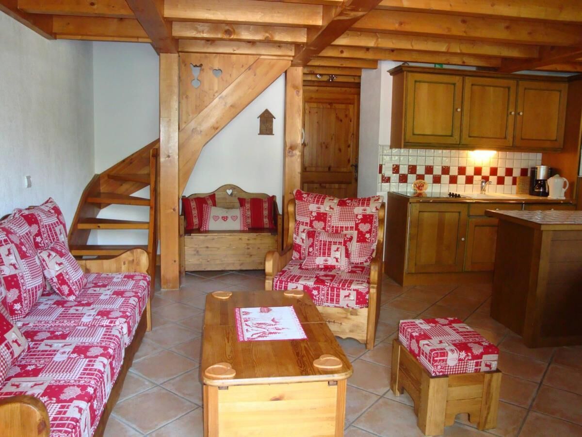 Un salon chaleureux avec un escalier en bois, un canapé, un fauteuil et une petite table.
