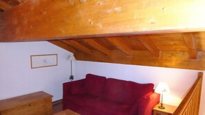 A cozy room with a red sofa, wooden table, and a lamp.