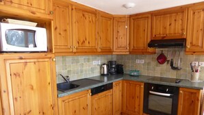 A kitchen with wooden cabinets, a microwave, a coffee maker, and a stove.