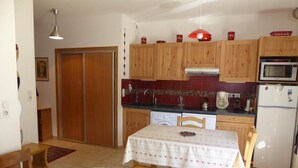 A compact kitchen with wooden cabinets, a microwave, a coffee maker, and a dining table with a tablecloth. - 200m from ski slopes, Ground floor, terrace, tv, ski locker, 43m², Pralognan-la-Vanoise (Pralognan-la-Vanoise)