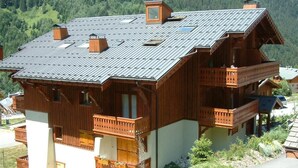 Un chalet in legno con tetto spiovente, diversi balconi e un camino.