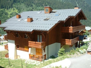 Eine Holzhütte mit geneigtem Dach, mehreren Balkonen und einem Schornstein.