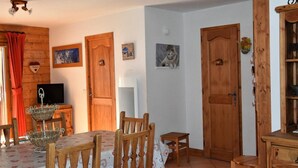 Un soggiorno accogliente con pareti e porte in legno, un tavolo da pranzo con sedie, una televisione e diverse decorazioni a parete.