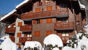 Una cabaña de madera con varios balcones y un tejado cubierto de nieve, rodeada de nieve.