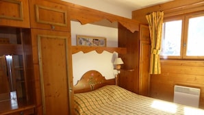 Une pièce en bois avec un lit, un bureau et une fenêtre avec des rideaux.