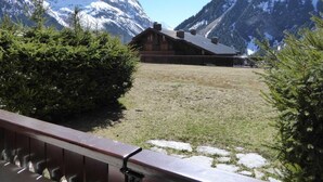 Un chalet de montagne aux murs en bois, entouré de sommets enneigés et surplombant un ciel dégagé.