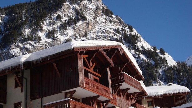 Un chalet doté de balcons en bois et surplombant un paysage montagneux.
