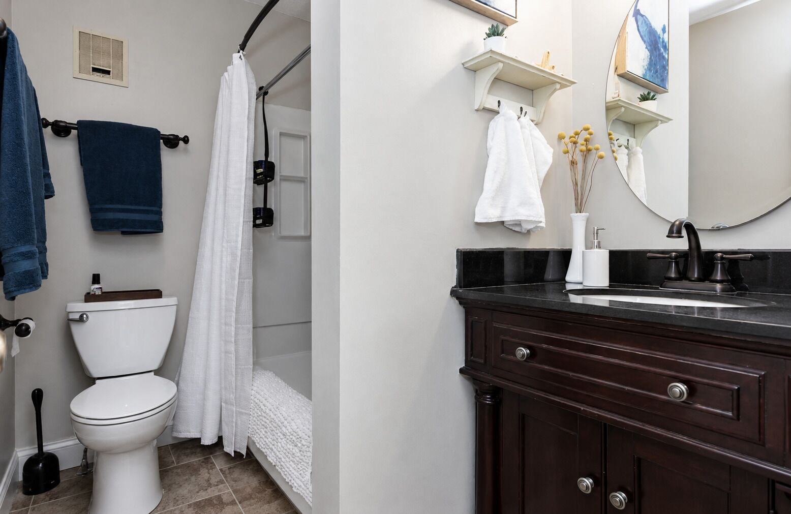 Un baño con inodoro, cortina de ducha, lavabo con espejo y toallero.