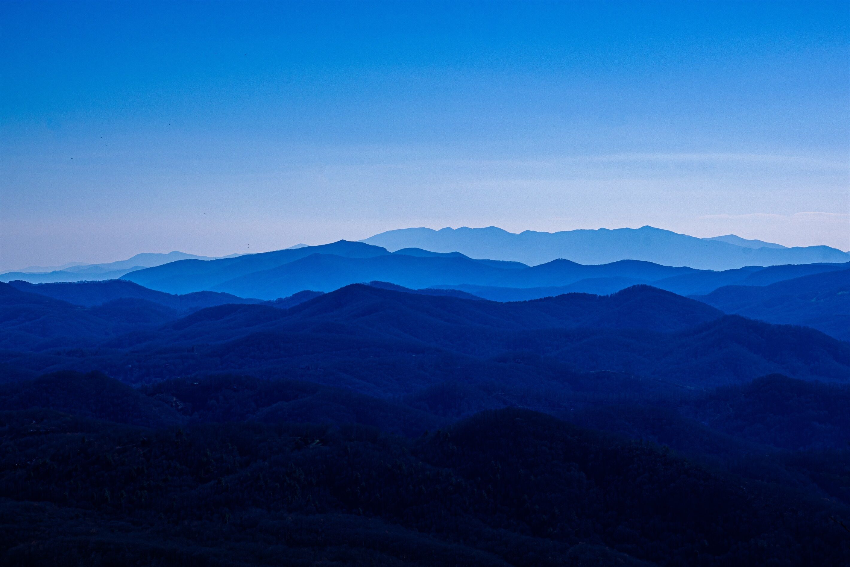 Un paysage montagneux avec des collines douces et un ciel dégagé.