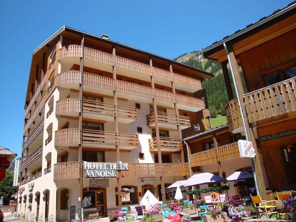 A multi-story hotel with balconies, a bar, and outdoor seating with umbrellas.