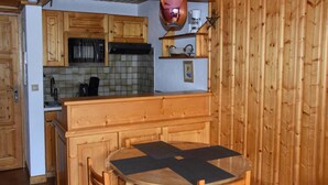 Eine Holz-Küche mit einem runden Tisch und Stühlen, einer Pendelleuchte und Holzschränken.