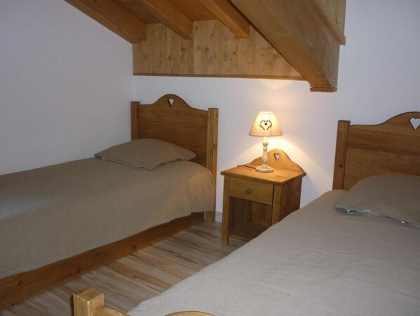 Une chambre avec deux lits en bois, une table de chevet avec une lampe et un plafond en bois.
