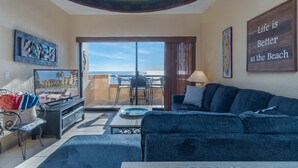 Una sala de estar con vista a la playa, un sofá, una mesa y un televisor.