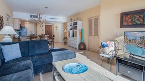 Una sala de estar con un sofá, una mesa de centro, un televisor y un comedor con mesa y sillas.
