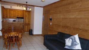 Un salon avec un canapé bleu foncé et une table à manger en bois, accompagnée de chaises.
