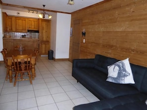 Un salon avec un canapé bleu foncé et une table à manger en bois, accompagnée de chaises.