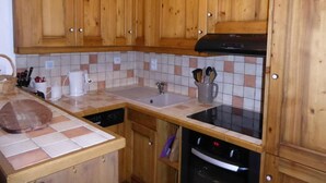 Une cuisine avec des meubles de rangement en bois, un pare-feu en carrelage, un évier, une cuisinière et un lave-vaisselle.