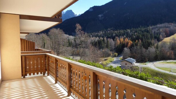 Un balcon doté d’une balustrade en bois, d’où l’on peut admirer un paysage montagneux.