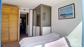 Ein Schlafzimmer mit einem Bett, einem Holzschrank, einem Spiegel und einem gerahmten Bild an der Wand.