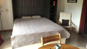 Ett sovrum med en säng, en stol, ett bord och en lampa.