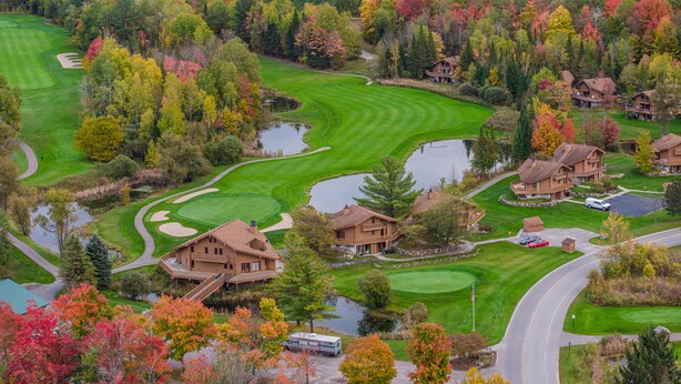 Un campo de golf con club house, estanques y árboles de colores otoñales.