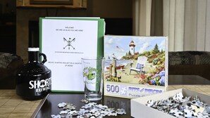 Una mesa con un rompecabezas, una botella y una tarjeta.