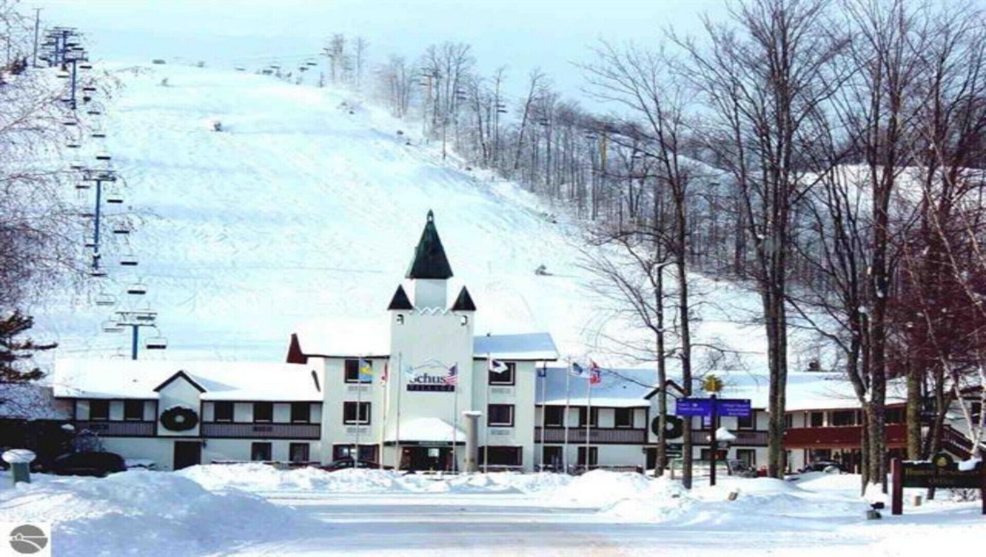 Ein Hotel mit einem zentralen Turm, zahlreichen Fenstern und einer Skipiste im Hintergrund.