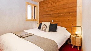 A bedroom with a wooden headboard, a bed with white bedding, a bedside table with a lamp, and a window. - Chalet, wifi, 50m from ski slopes, sauna, balcony, fireplace or stove, parking, tv, ski locker (Bellentre)