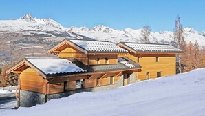 A wooden chalet with a sloped roof, set against a snowy mountain backdrop. - Chalet, wifi, 50m from ski slopes, sauna, balcony, fireplace or stove, parking, tv, ski locker (Bellentre)