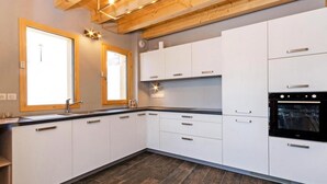 A modern kitchen with white cabinets, a black countertop, and a built-in oven. - Chalet, wifi, 50m from ski slopes, sauna, balcony, fireplace or stove, parking, tv, ski locker (Bellentre)