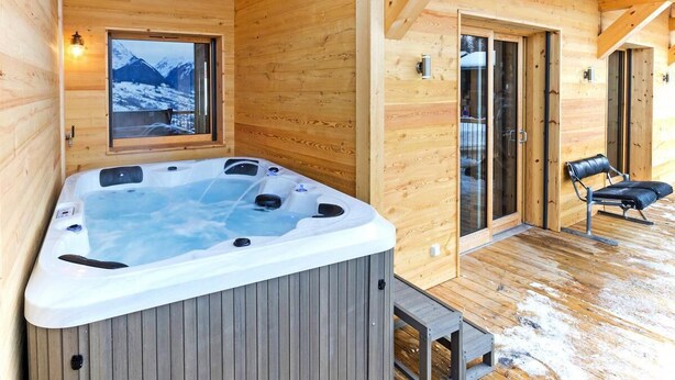 A wooden cabin with a hot tub, a glass door leading outside, and a bench. - Chalet, wifi, 50m from ski slopes, sauna, balcony, fireplace or stove, parking, tv, ski locker (Bellentre)