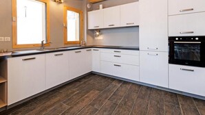 A modern kitchen with white cabinets, a black countertop, and a built-in oven. - Chalet, wifi, 50m from ski slopes, sauna, balcony, fireplace or stove, parking, tv, ski locker (Bellentre)