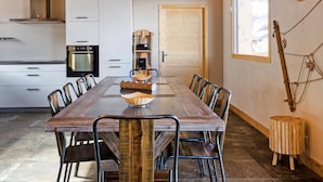 A dining area with a long wooden table, metal chairs, and a central woven bowl. - Chalet, wifi, 50m from ski slopes, sauna, balcony, fireplace or stove, parking, tv, ski locker (Bellentre)