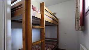 A room with two bunk beds, a radiator, and a window with curtains.