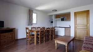 A compact living space with a dining area, kitchenette, and a sofa.