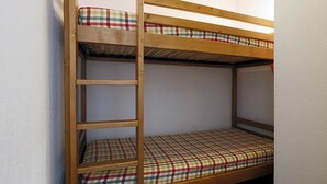 A bunk bed with a wooden ladder and plaid bedding.