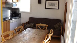 Una cocina compacta con una mesa y sillas, un sofá, y un cuadro en la pared.