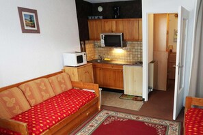 Cozy kitchenette with microwave and refrigerator. Comfortable seating area with sofa and rug.